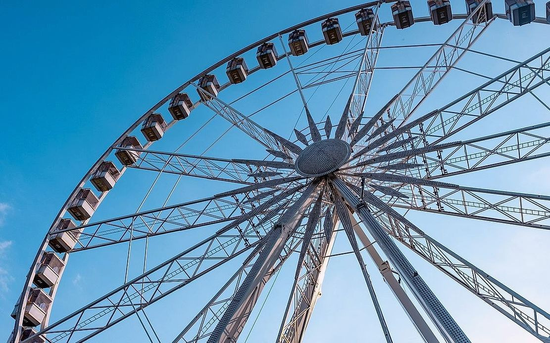 Des montagnes russes en acier épousant les courbes du parc, les visiteurs les mains en l'air